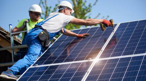 panelessolares Two workers technicians installing heavy solar photo voltaic panels to high steel platform. Exterior solar system installation, alternative renewable green energy generation concept.
