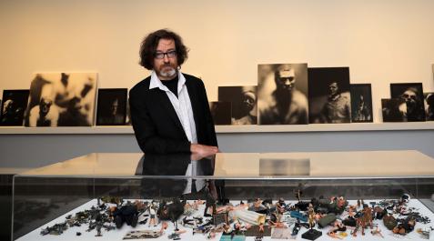 Ribalta posa junto a una serie de retratos basados en diferentes personajes, tanto históricos como de ficción. En la vitrina se acumulan personajes u objetos que han inspirado las fotografías Ribalta posa junto a una serie de retratos basados en diferentes personajes, tanto históricos como de ficción. En la vitrina se acumulan personajes u objetos que han inspirado las fotografías