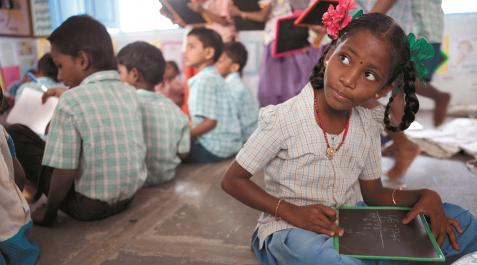 Una niña india escribe unos números en su pizarra, en la escuela Una niña india escribe unos números en su pizarra, en la escuela