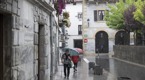 Lesaka Una persona se protege de la lluvia mientras camina por la plaza Zaharra.