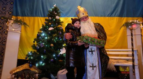 SKOLE (UCRANIA). San Nicolás entrega el regalo de Teresa Uriarte a Katerina, una niña a la que su madre tuvo que tapar los ojos bajo los bombardeos mientras huían de su pueblo hacia Skole. Skole