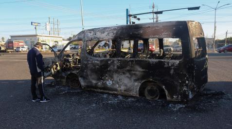 Un hombre se para junto a los restos quemados de un vehículo tras la ola de violencia Un hombre se para junto a los restos quemados de un vehículo tras la ola de violencia