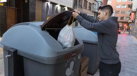 Un joven introduce una bolsa en el contenedor marrón para materia orgánica de la calle Capuchinos de Tudela Un joven introduce una bolsa en el contenedor marrón para materia orgánica de la calle Capuchinos de Tudela