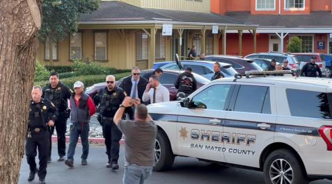 Agentes de la Policía con un hombre detenido tras el tiroteo en Half Moon Bay, en California