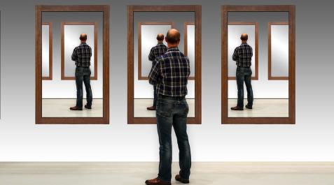 Un hombre observa su imagen repetida en varios espejos