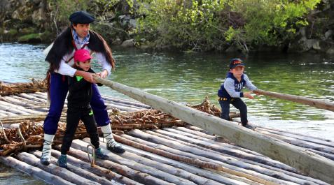 Un hombre y dos niños navegan el Esca en Burgui el día de la almadía Un hombre y dos niños navegan el Esca en Burgui el día de la almadía