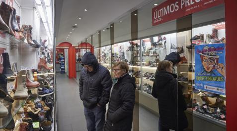 Dos personas observan las ofertas de una zapatería en el Casco Antiguo pamplonés Dos personas observan las ofertas de una zapatería en el Casco Antiguo pamplonés
