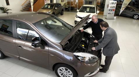 El empleado de un concesionario enseña un coche a un cliente El empleado de un concesionario enseña un coche a un cliente