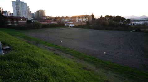 Vista de los terrenos destinados a vivienda en la nueva urbanización. Al fondo, el Pueblo Viejo
