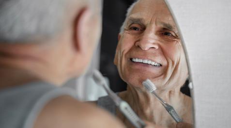 Un hombre observa en el espejo los efectos en sus dientes tras cepillárselos