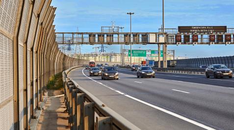 Paneles informativos en una carretera St. Petersburg, Russia - August 28, 2018: cars are driving under the road sign on the ring road with noise barrier fence and steel beam crash barrier.
