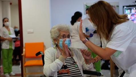 Una anciana de una residencia de ancianos celebra con una enfermera la tercera dosis de la vacuna contra el coronavirus
