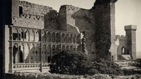 La imagen presenta el Palacio en proceso de restauración con los arcos de la Galería del rey y la torre de los Cuatro Vientos, a la derecha de la imagen, ya consolidados y restaurados