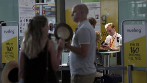 Personal de facturación de Vueling atiende a los viajeros en el Aeropuerto de El Prat.