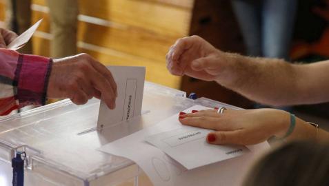 Un hombre introduce su voto en una urna durante las elecciones generales.