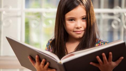 Una niña leyendo un libro.