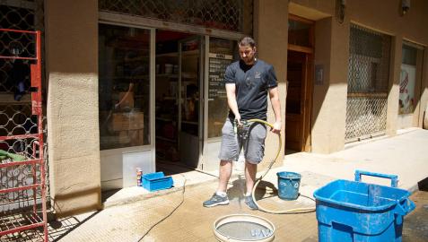 Un comerciante limpia las inmediaciones de su establecimiento tras las lluvias torrenciales del 8 de julio pasado