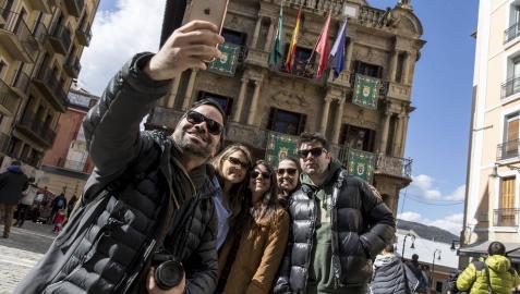 Unos turistas se hacen una foto delante del Ayuntamiento de Pamplona