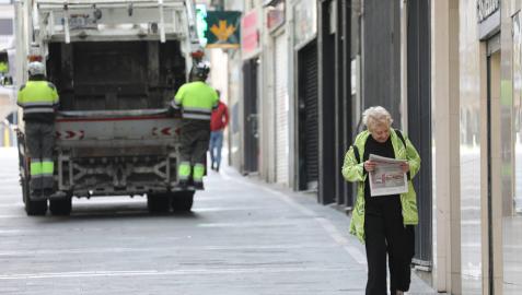 Una mujer regresa de comprar el pan y la prensa en Pamplona. Al fondo, el servicio de recogida de basuras, que sigue funcionando. Una mujer regresa de comprar el pan y la prensa en Pamplona. Al fondo, el servicio de recogida de basuras, que sigue funcionando.
