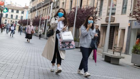 Dos jóvenes, con bolsas de compra, pasean por la calle Gaztambide-Carrera de Tudela.
