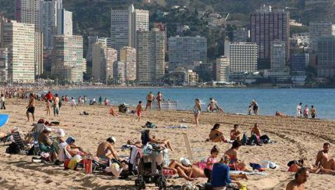 Turistas disfrutando del sol en la playa de Benidorm.
