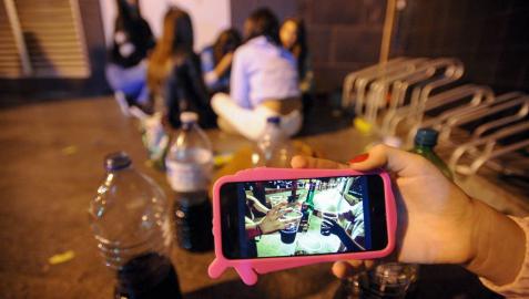 Un grupo de adolescentes hace botellón en la calle.