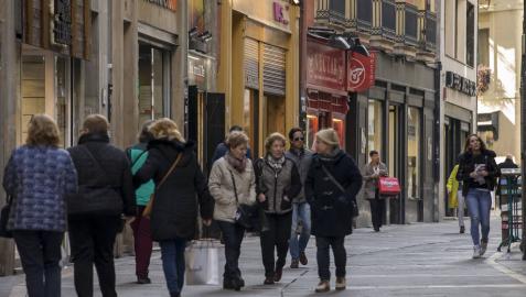 Varios grupos de personas pasean en la calle Zapatería, del Casco Viejo de Pamplona, con bolsas de compras.