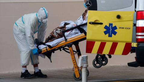 Un sanitario traslada a un enfermo de coronavirus en el Hospital Clínico de Valencia.