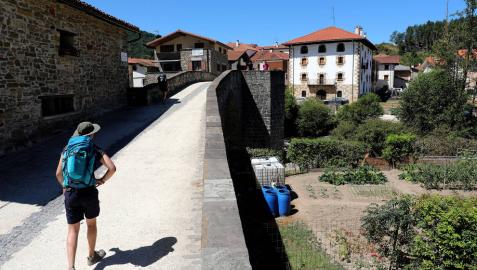 Imagen de un peregrino que cruza el Puente de la Rabia de Zubiri situado en el recorrido del Camino de Santiago