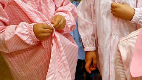 Varios niños con sus batas en un colegio.