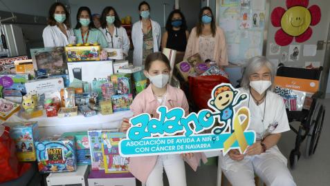 Solidaridad infantil. De izda a dcha: Anne Alzuguren López (niña que ha donado) y María Sagaseta de Ilúrdoz (médico oncología pediátrica) sujetando el cártel de la asociación Adano. Detrás: Desirée Morales (médico oncología), Beatriz Ramos (MIR pediatría), Miren Oscoz (médico oncología), Marta Martínez (médico oncología), Michelle Morillo (trabajadora social de Adano) y Amaia Barbero (psicóloga Adano), en el hospital de día infantil del CHN