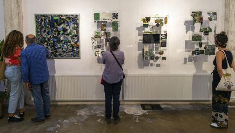 Varias personas observan distintas piezas creadas por Leo Pum, obras que el artista realiza con objetos obsoletos mediante la técnica de la técnica de la fotogrametría.