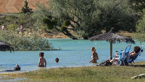 Una familia descansa en la zona de baño de Lerate en el embalse de Alloz mientras los niños se bañan.