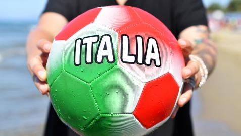 Un aficionado sujeta yun balón con los colores de Italia en la playa de Castiglione della Pescaia