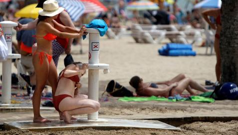 Dos mujeres tratan de refrescarse en los lavapaies de la playa de El Postiguet de Alicante
