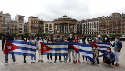Un grupo de ciudadanos cubanos despliega las banderas del país en la Plaza del Castillo de Pamplona