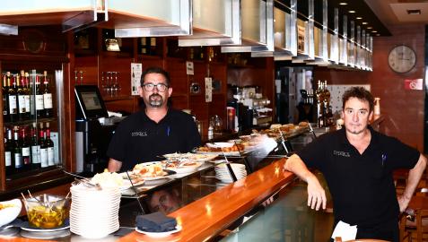 Eduardo Zubieta posa en la barra del bar StickBol repleta de pinchos junto a otro camarero