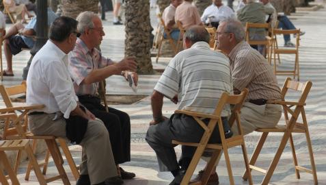 Un grupo de personas mayores conversa en un pequeño corro al aire libre
