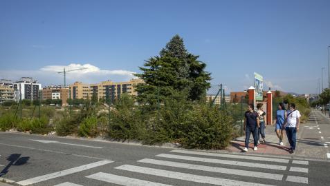 Un grupo de personas pasa por la acera de la avenida Gupúzcoa junto al solar que cobijará un cubo comercial y viviendas