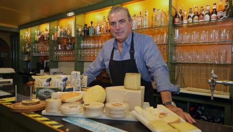Aitor Otazu Larrauri posa en la barra del bar Savoy con varias tablas de queso