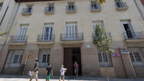 Varias personas pasean ante la fachada de la biblioteca de Tudela, situada en la calle Herrerías