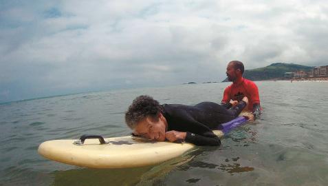 Marian Cano, tumbada sobre una tabla de surf, con un monitor de ‘MOOR Surf Eskola’, en Zarautz (Guipúzcoa), el pasado 3 de julio