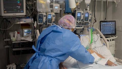 Un sanitario atiende a un paciente ingresado por covid en el Hospital Clínic de Barcelona