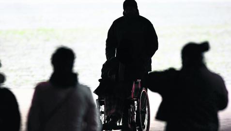 Una persona pasea a otra en silla de ruedas por el centro de Pamplona