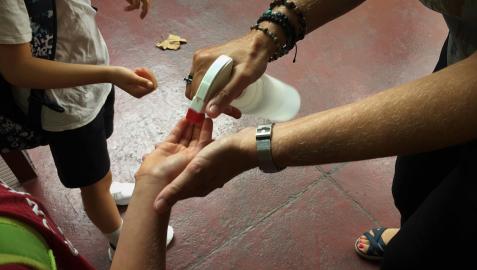 Una maestra dispensando gel hidroalcohólico a unos alumnos en el primer día del curso