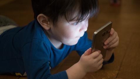 Imagen de archivo de un niño usando un teléfono móvil.