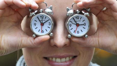 Una mujer cubre sus ojos con dos relojes