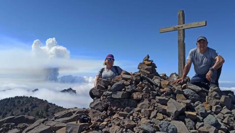 Mikel Aznárez y Malu Bojan Arregui, ayer al mediodía en La Palma, en el Pico de la Nieve. Al fondo, la columna de humo y vapor del volcán