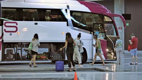 Varios viajeros esperan para subir a un autobús interurbano