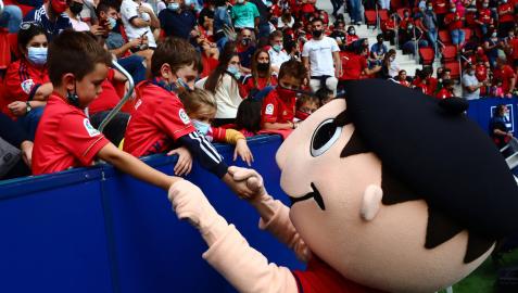 La mascota Rojillo saluda a dos jóvenes aficionados